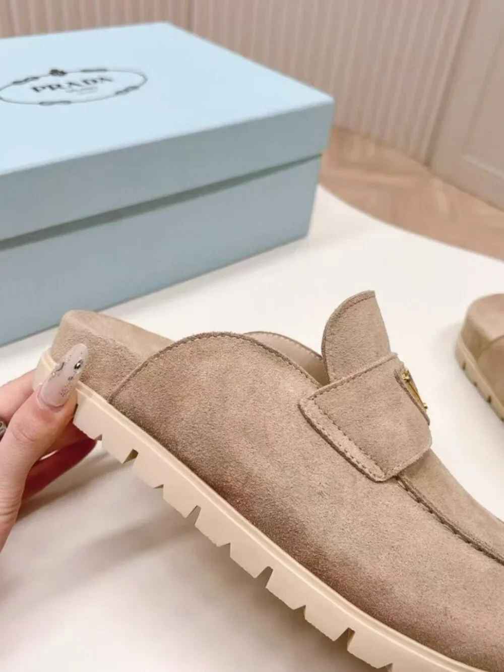 Prada beige slip‑on mules with triangular logo badge